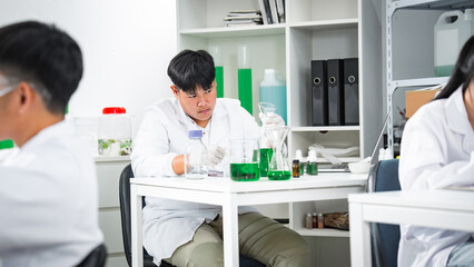Young scientist conducting algae biotechnology research in a modern laboratory, analyzing green liquid samples for sustainable bioenergy, environmental innovation, and renewable resource development.