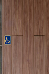 Wheelchair accessibility icon painted on a wooden surface in a car park, symbolizing disabled access and inclusive design.