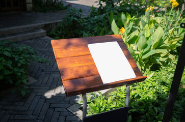 Blank white paper on a menu stand displayed at a restaurant entrance, ideal for mockup, announcement, or promotional use.