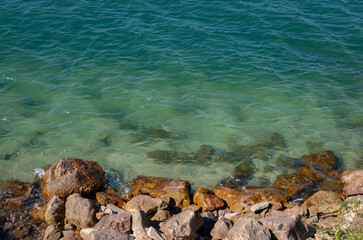 Rocky shoreline with clear seawater and natural textures, capturing a peaceful coastal landscape under daylight.