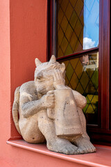Close-up of a seated stone figure shaped like a devil holding a jug on a windowsill