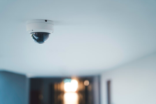Ceiling mounted CCTV security camera in a modern indoor hallway for surveillance and continuous monitoring for safety crime prevention smart building technology and professional security systems.