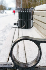 Close-up of Park Bench with Iron Armrest Covered in Fresh Snow