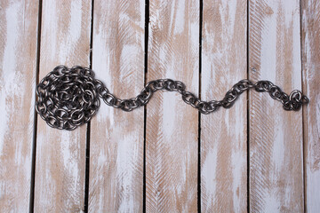 Roll of new metal chain on the plank background