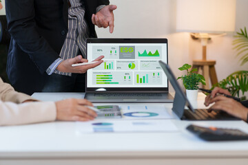 Group of business professionals analyzing an ESG performance dashboard on a laptop during a corporate meeting to discuss sustainable investing and data analytics.