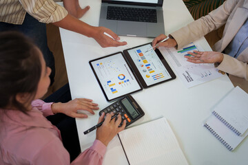 Business team analyzing sales data and financial performance charts on digital tablets during a collaborative office meeting.