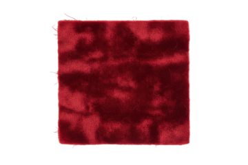 Textural study of a rich velvet square with soft lighting on a red surface