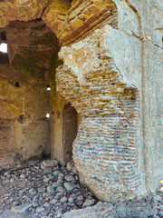 Ancient ruins of a red brick structure with crumbling mortar, historic masonry details, and weathered architectural textures.