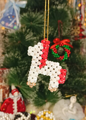Handmade beaded horse ornament in white, gold and red colors, decorated as a festive Christmas and New Year decoration. Symbol of the Year of the Horse 2026. Hanging against the background of the tree