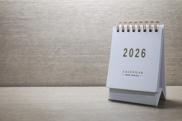 Small white calendar year 2026 on wooden table, with copy space.