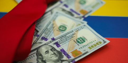 United States dollars and a red necktie on the national colors of the Venezuelan flag background. Shallow depth of field.