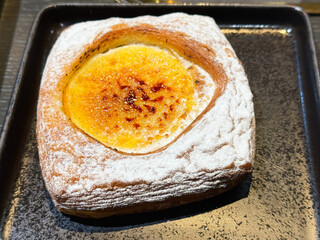 Cream puff pastry sprinkled with powdered sugar on black plate