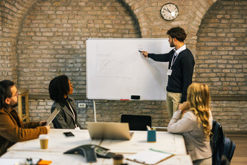 Young businessman writing on whiteboard during presentation