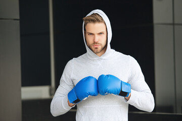 Sportsman in boxing gloves outdoor. Young man boxer. Sport man boxing. Strong athlete man. Sportsman in hoodie. Strong boxer in sportswear. Exercising and punching. Practicing boxing, copy space