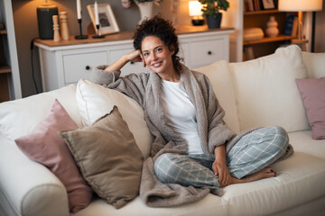 Obraz premium Cozy Woman Relaxing On White Couch In Comfortable Robe At Home