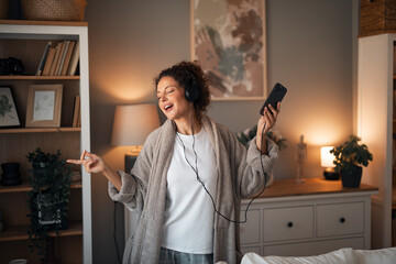 Woman Singing and Dancing at Home With Headphones and Phone in Cozy Living Room