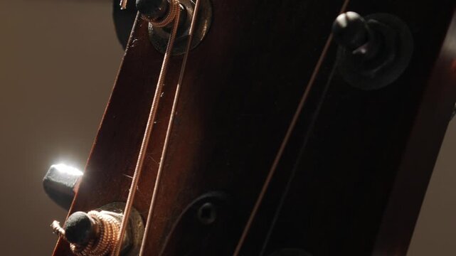Guitar Headstock Side View: Wooden Neck with Tuning Pegs and Strings Close-up on Classic Acoustic Musical Instrument