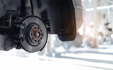Closeup of car brake disc and caliper in sunlit garage workshop, sunlight