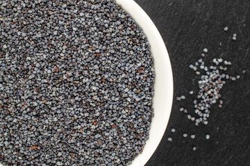 Dry poppy with kitchen utensils on slate stone, macro, top view.