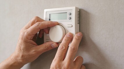 senior Hands adjusting a wall thermostat Retirement Living concept