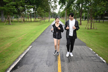 Asian Friends running together on a rainy day, wearing light jackets and smiling as they stay active outdoors