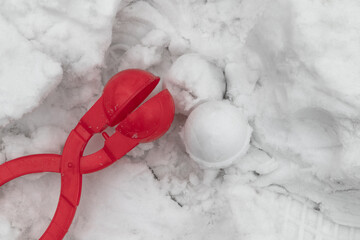 Red snowball maker on white snow in winter