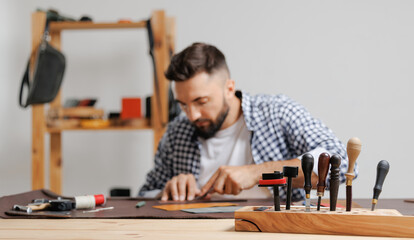 Tailor cobbler hold different rolls natural brown leather, working with textile in workshop