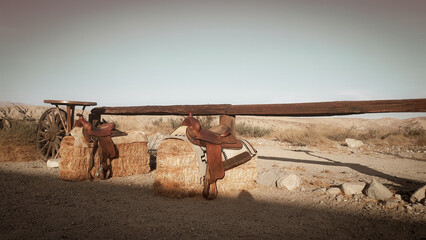 Western atmosphere with saddles on hay and vintage wooden fence in sunlight © Jasmin