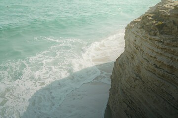 Calm coastal moment caught as soft morning hues drift gently across rugged textured cliffs