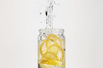 Fresh lemon slices floating in clear glass bottle filled with sparkling water