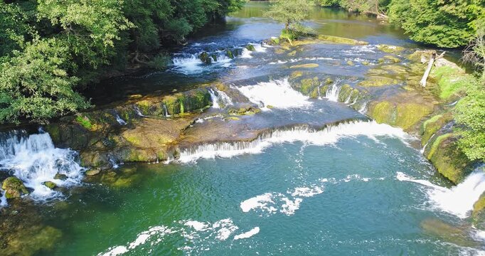 Aerial view of river rapids and small waterfalls in forest landscape in Slovenia
