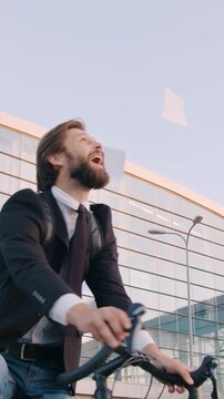 Good results business concept man office manager with beard scattering financial documents around him while biking near big city building with panoramic windows
