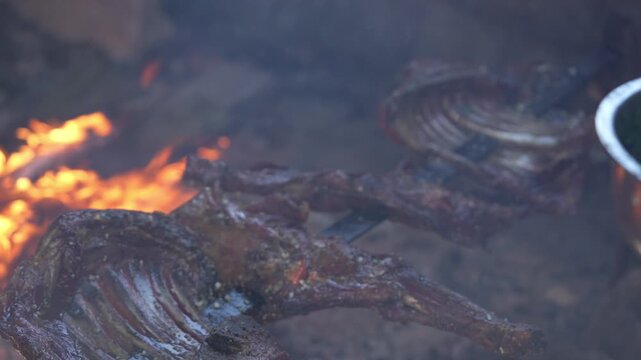 Traditional Patagonian lamb roasting over an open fire pit, slow-cooked meat, Asado de cordero al palo, classic Chilean and Argentine outdoor barbecue