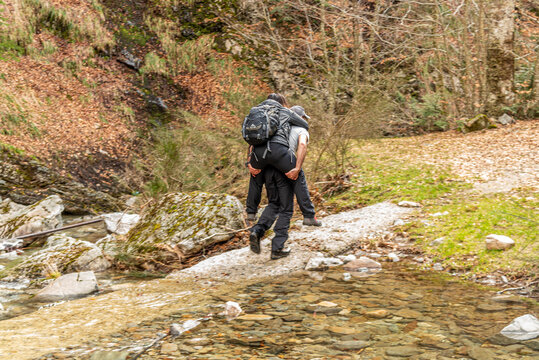 Ragazzo prende in spalla una ragazza per attraversare un corso d'acqua senza farla bagnare
