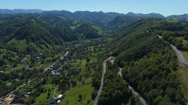 Lateral Aerial Reveal of Moieciu de Jos Village End and Bucegi Mountains over Pastoral Hayfields