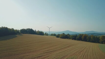 Sustainable Energy Landscape: Wind Turbine in Golden Fields with Distant Mountains Under Hazy Sky