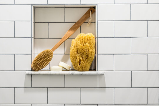 Bath sponge and scrubber in white subway tile shower niche