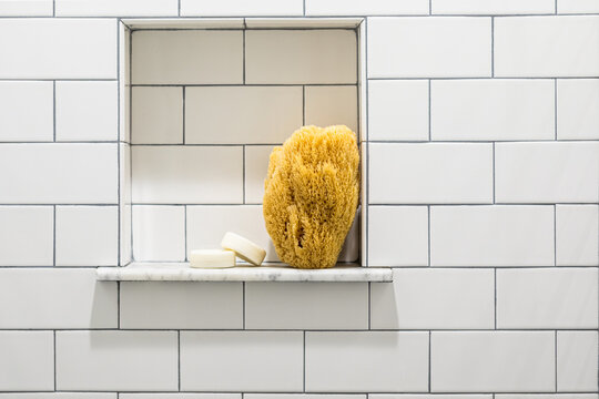 Bath sponge and scrubber in white subway tile shower niche