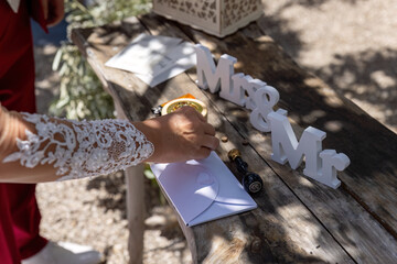 Bride sealing wedding envelope with wax stamp on rustic wooden table with decor