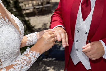 Bride placing wedding ring on groom&rsquo;s finger during outdoor ceremony
