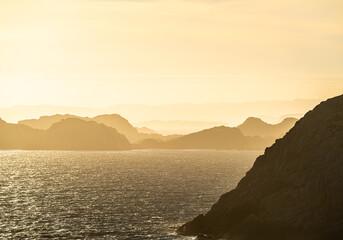 Golden coastal mountains fading into atmospheric seaside horizon.