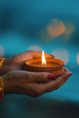 Hands holding lit oil lamp for Diwali celebration. Festival of lights concept.