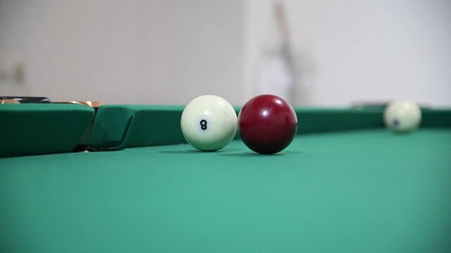 Hitting the ball with a cue and hitting the hole on the green background of the billiard table
