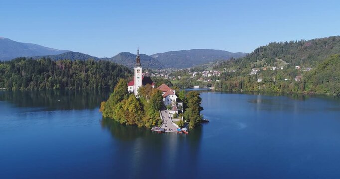 Aerial approach toward Bled Island with church and alpine scenery