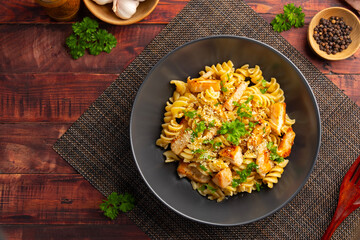 eliche pasta with chicken.Creamy garlic with grilled chicken breast and eliche pasta in black plate.
