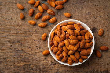Dry roasted Almonds in white plate on wooden table.Heap of almond.Top view
