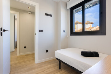 Small minimalist bedroom with single bed, window view, and light wooden flooring