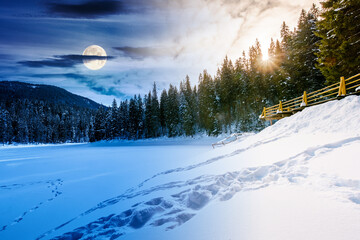 snow covered frozen lake in natural park. day and night time change concept. winter solstice landscape surrounded with coniferous forest in mountains with sun and moon. harmony and progress calendar