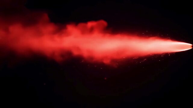 Intense red jet stream fire shooting horizontally. Rocket thruster exhaust with flying sparks and smoke.