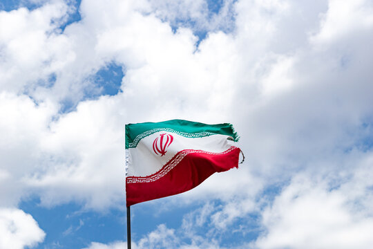 iranian flag waving against a clear blue sky on a flagpole. Flag of Iran Islamic Republic